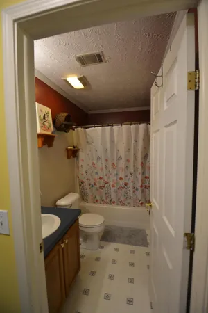a bathroom with a granite countertop sink a toilet a mirror and shower