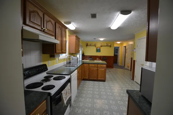 a kitchen with stainless steel appliances kitchen island granite countertop a stove and a sink