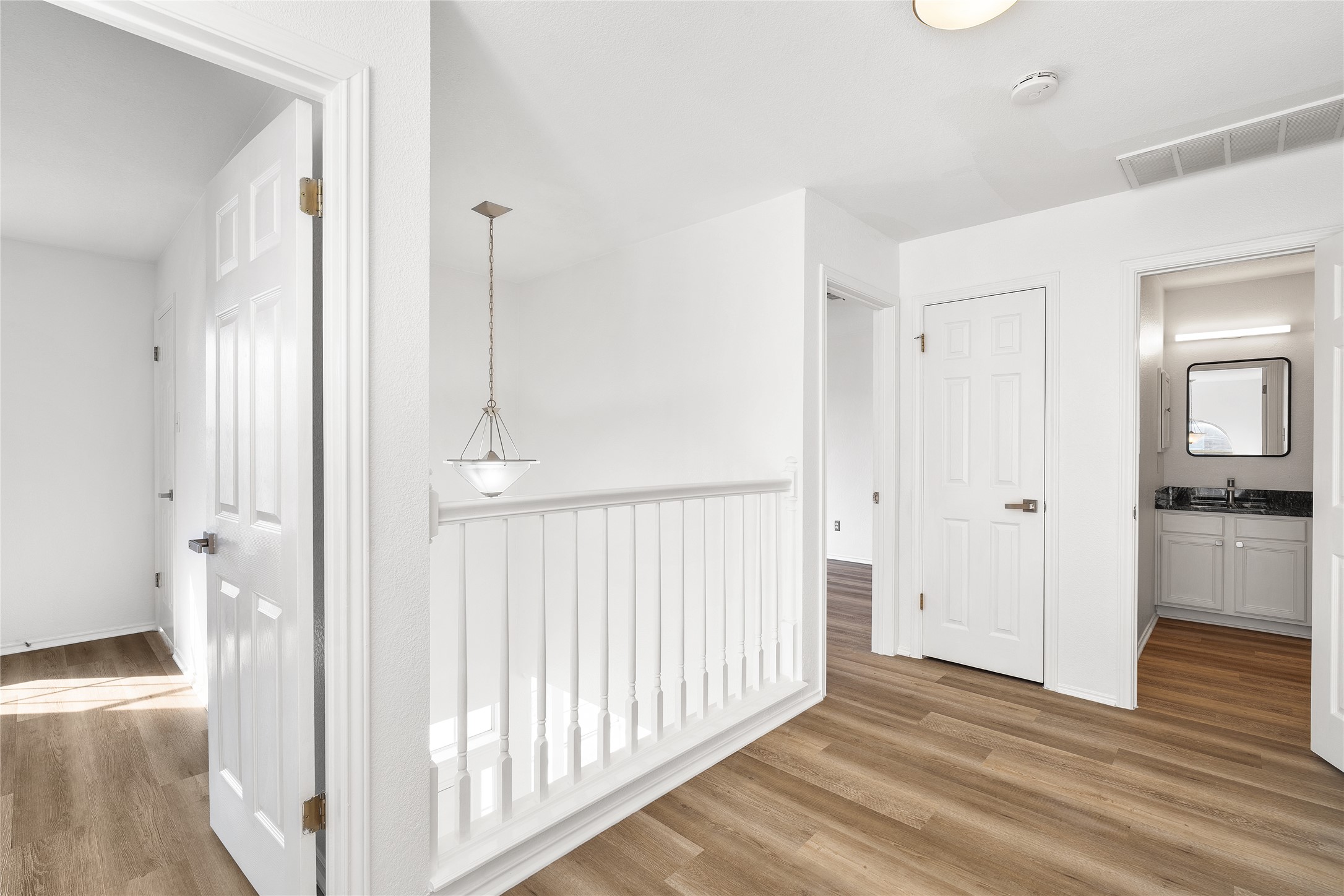 206 River Down Road Georgetown, TX 78628 - Photo 22 of 39 Upper-level landing featuring wood-finish flooring, white baluster railing, a pendant light fixture, and a built-in ceiling light