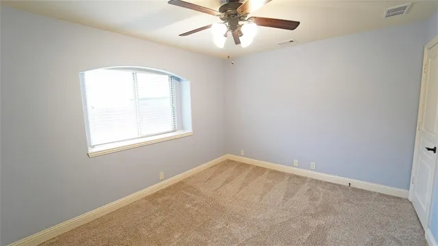 an empty room with a window and a fan
