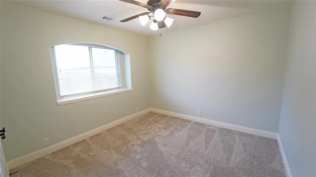 an empty room with a window and a fan