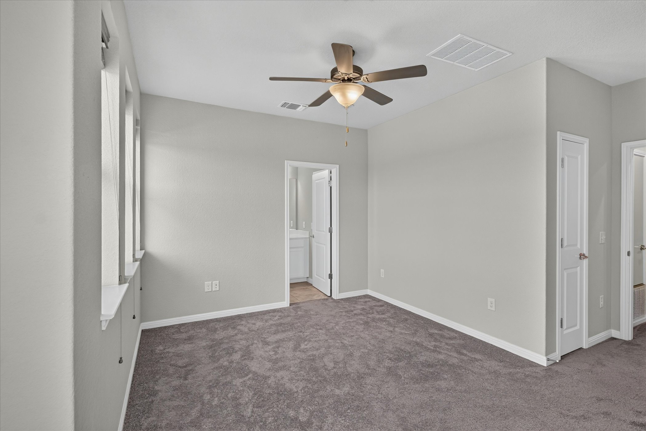 9015 Cattle Baron Path, Unit 1102 Austin, TX 78747 - Photo 17 of 25 A quiet retreat with carpeted floors and a ceiling fan, offering a private bathroom entrance.