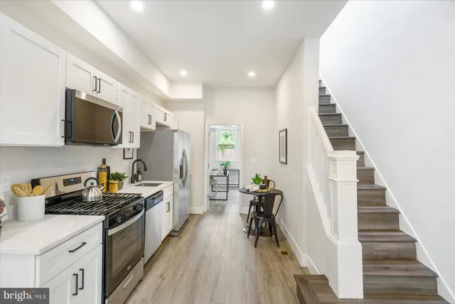 a kitchen with stainless steel appliances a kitchen island hardwood floor sink stove dining table and chairs