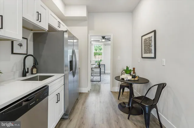 a kitchen with stainless steel appliances granite countertop a stove top oven a sink dishwasher and white cabinets with wooden floor