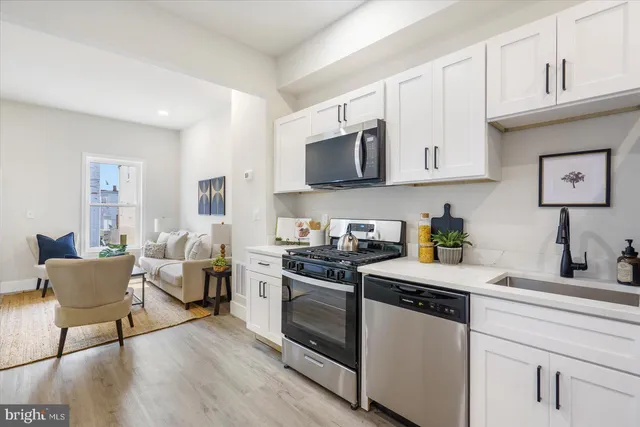 a kitchen with granite countertop a stove a microwave a sink and cabinets