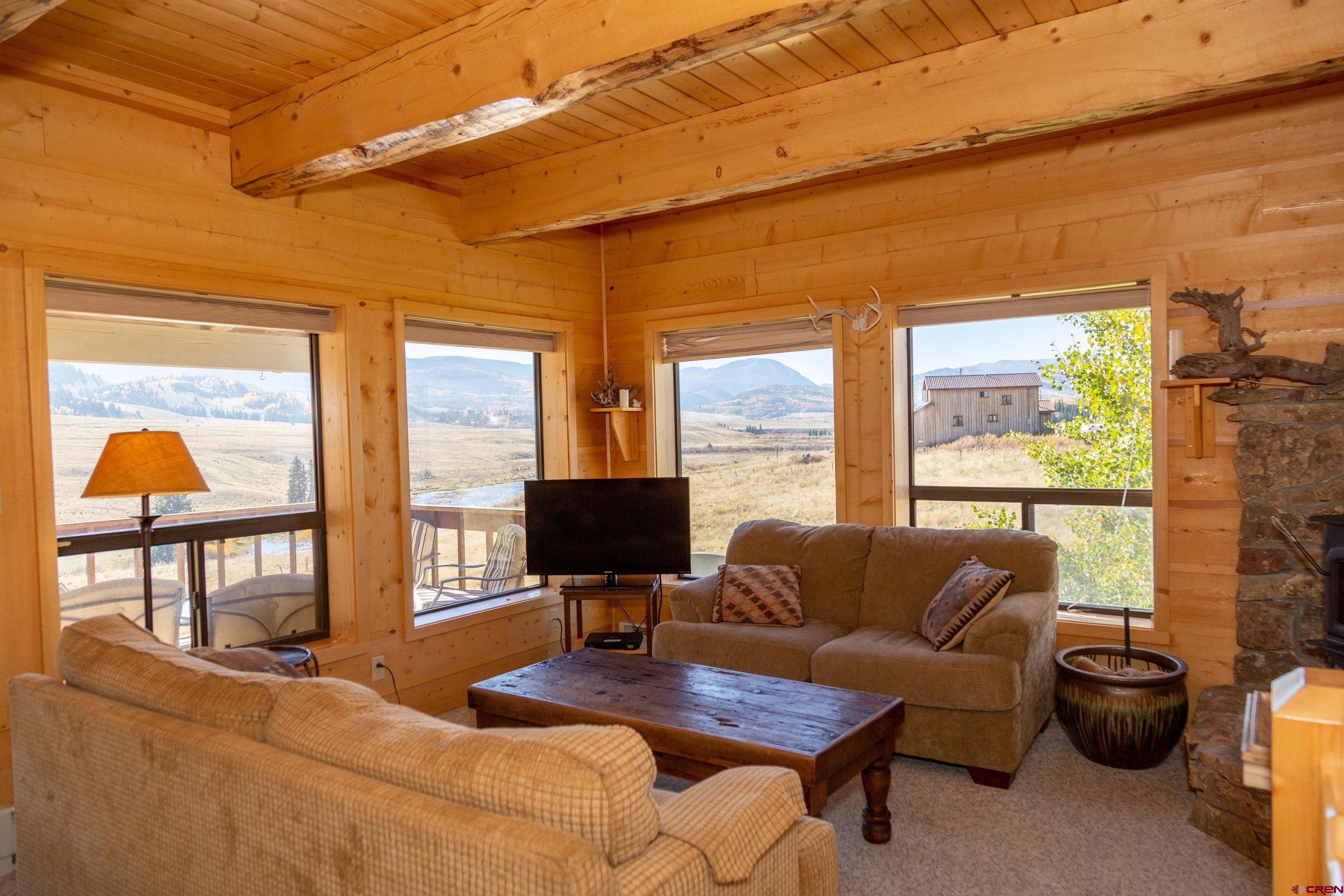 516 Rio Grande Court Creede, CO 81130 - Photo 13 of 33 a living room with furniture a flat screen tv and a floor to ceiling window