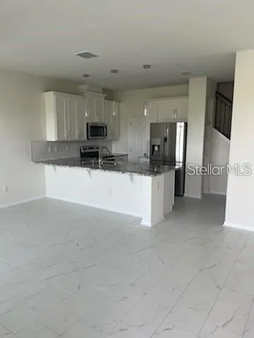 a kitchen with granite countertop a refrigerator stove and microwave