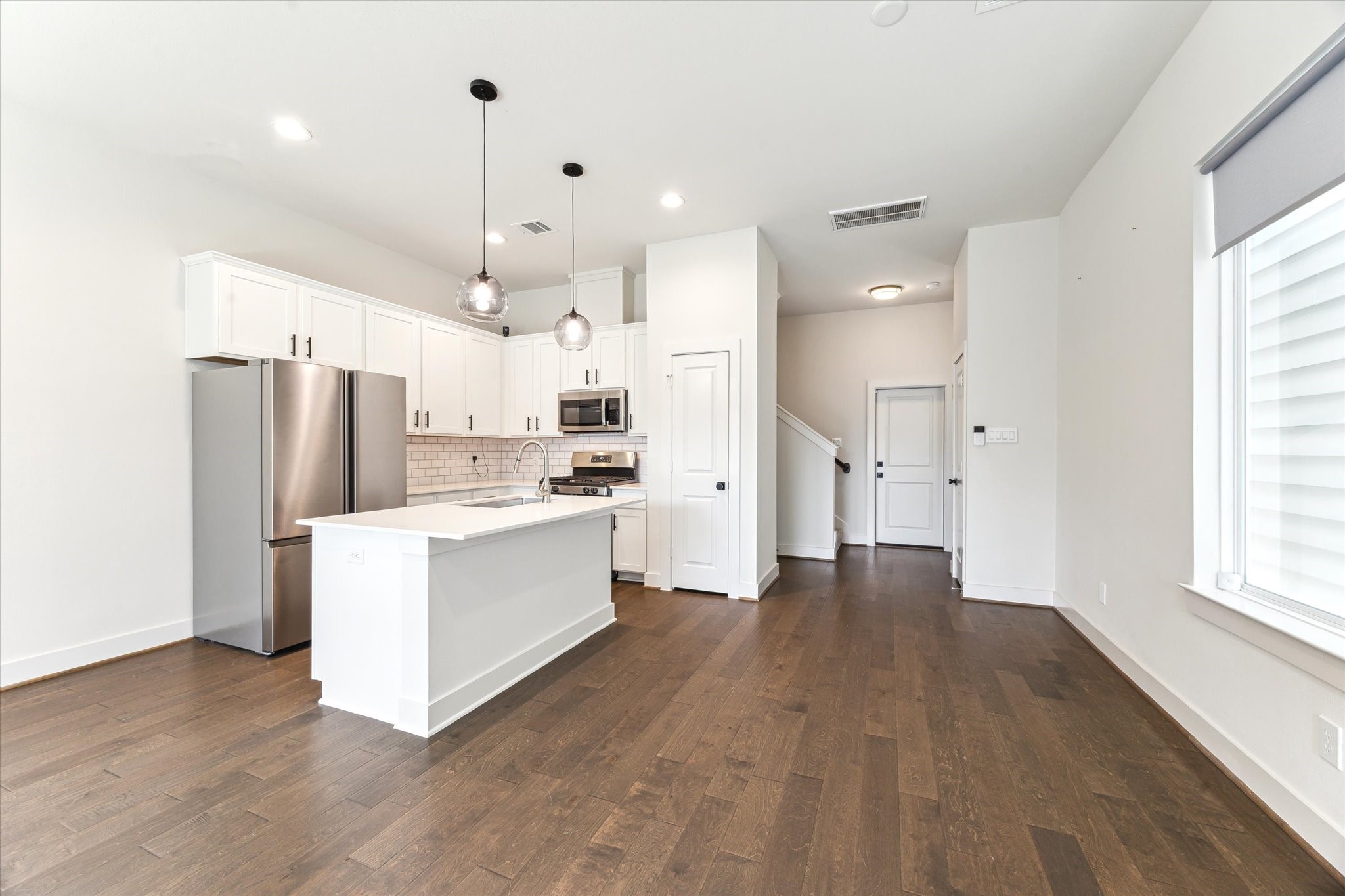 4155 Griggs Road Houston, TX 77021 - Photo 3 of 17 Sleek, open-concept kitchen with stainless steel appliances, quartz island, subway tile backsplash, and rich hardwood floors—modern style meets everyday function.