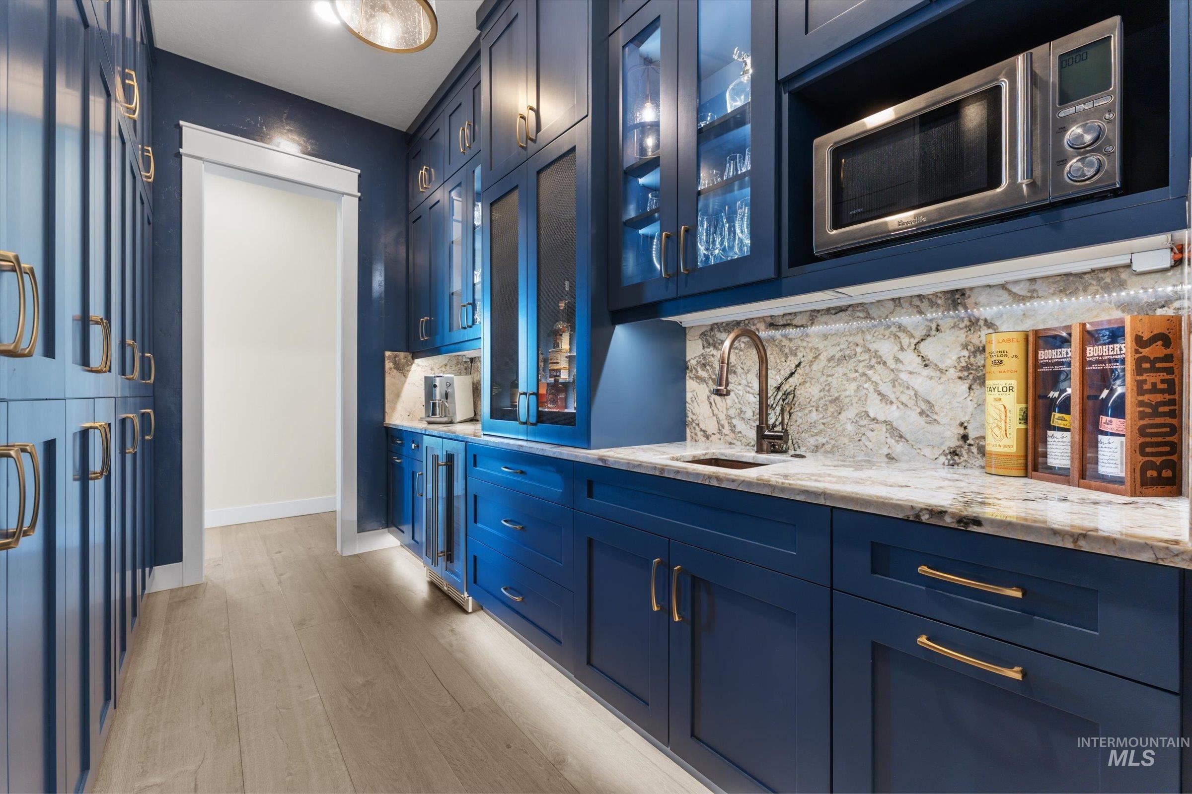 6585 South Pemberley Way Meridian, ID 83642 - Photo 18 of 43 Custom blue cabinetry featuring gold-tone hardware, a built-in microwave, and integrated under-cabinet lighting