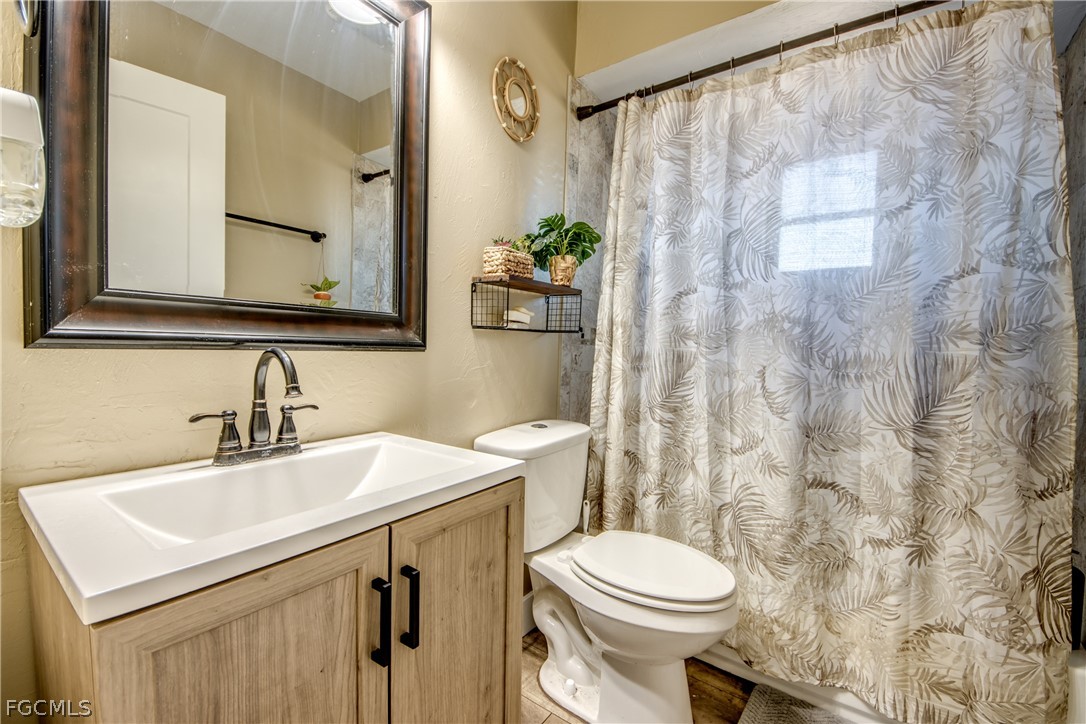 3015 8th Street Southwest Lehigh Acres, FL 33976 - Photo 23 of 34 a bathroom with a sink a toilet and shower curtain