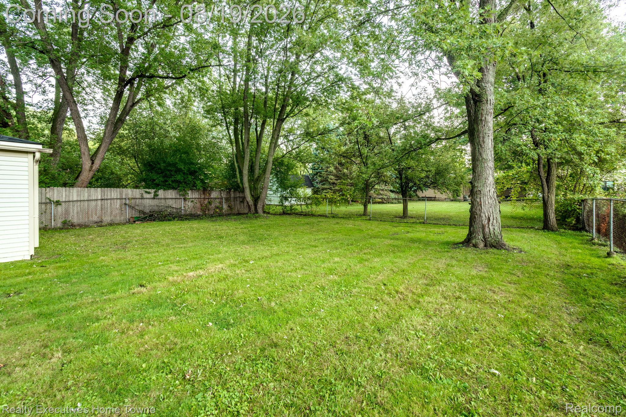 2448 Oakcrest Road Sterling Heights, MI 48310 - Photo 31 of 31 Expansive grassy yard with mature trees, a wood privacy fence, and a storage shed with horizontal siding