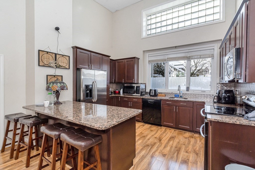 a kitchen with granite countertop a table chairs stove and refrigerator
