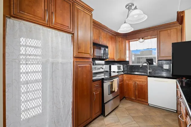 a kitchen with stainless steel appliances granite countertop a sink a stove a refrigerator cabinets and a dining table