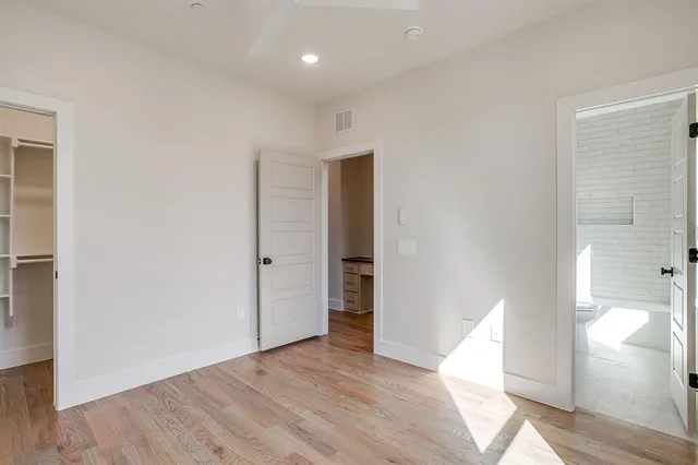 an empty room with wooden floor cabinet and windows