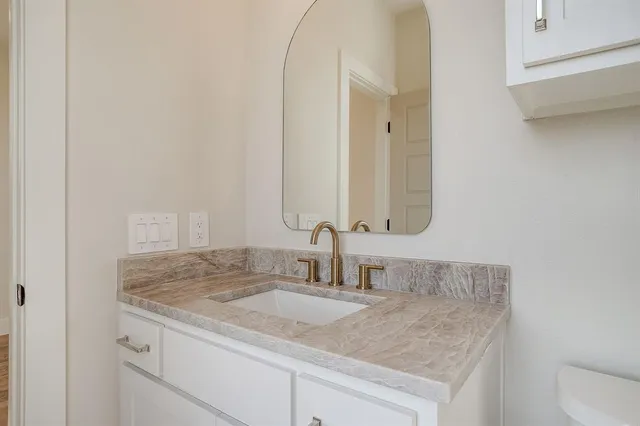 a view of an empty room with wooden floor and a bathroom