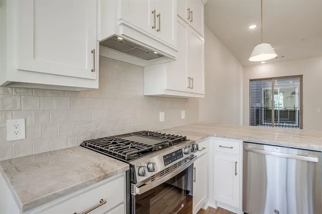 a kitchen with stainless steel appliances granite countertop a stove and a white cabinets