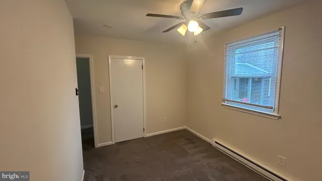 an empty room with a chandelier fan and windows