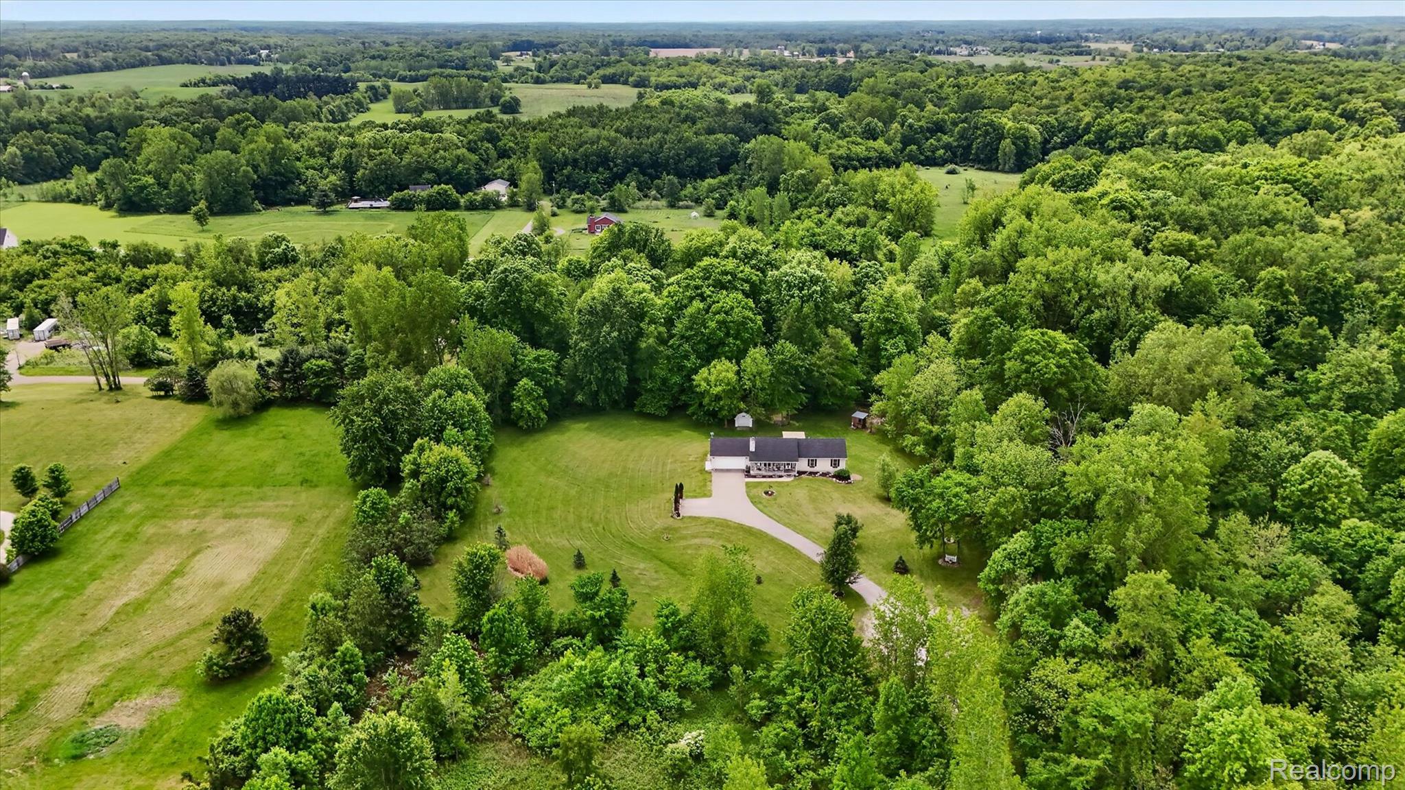 9565 Crofoot Road Fowlerville, MI 48836 - Photo 54 of 63 Expansive property featuring a single-story residence with a dark roof and light siding, set amidst abundant mature trees and open green spaces