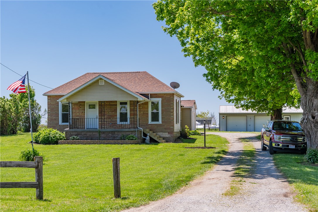 This charming home features a lovely front porch and a spacious driveway leading to a detached garage.