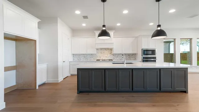 a large kitchen with stainless steel appliances granite countertop a sink a stove and a refrigerator