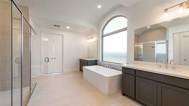 a spacious bathroom with a double vanity sink a mirror and a shower