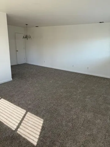 an empty room with a ceiling fan and carpet