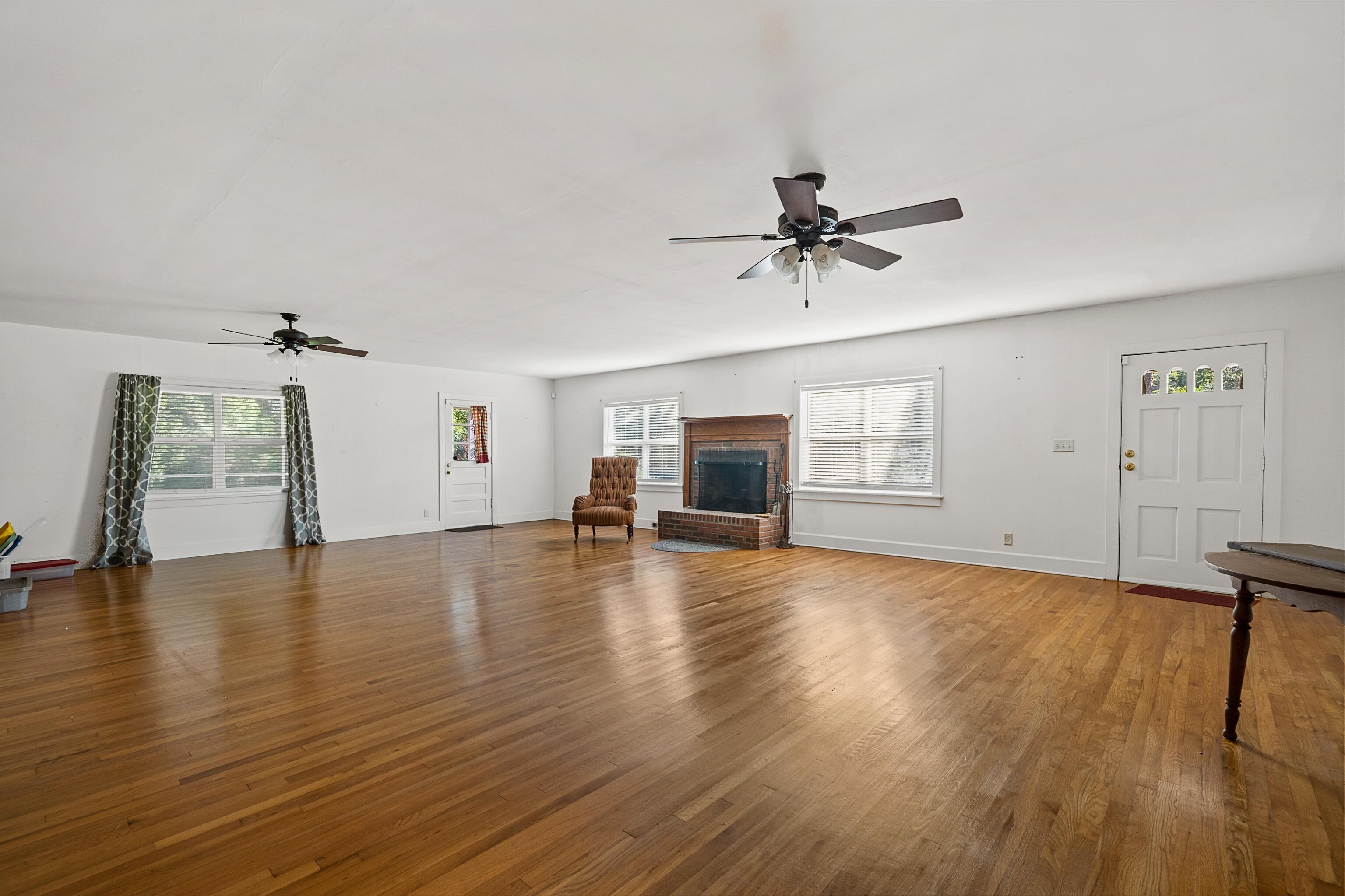 9350 Tompkins Road Stockton, AL 36579 - Photo 13 of 36 Unfurnished living room with a ceiling fan, wood finished floors, plenty of natural light, and a brick fireplace