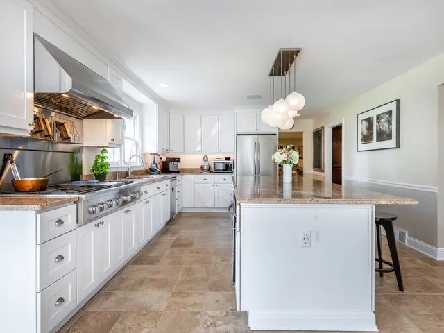 a kitchen with kitchen island granite countertop a sink a counter top space cabinets and stainless steel appliances