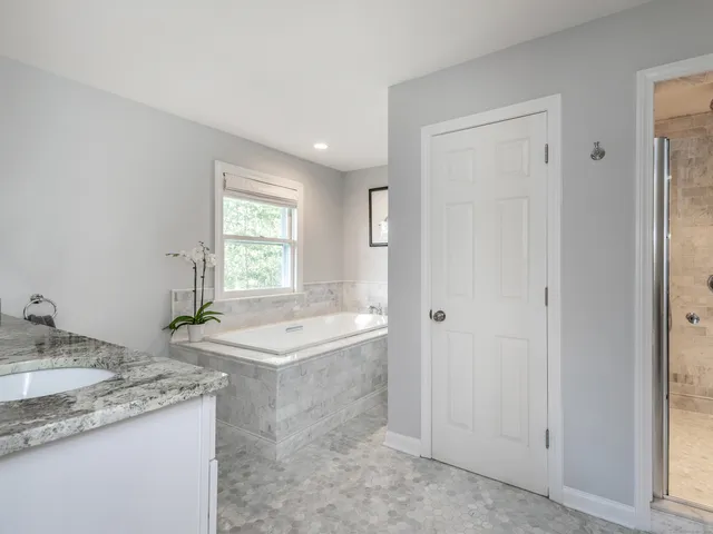 a bathroom with a granite countertop tub sink and mirror
