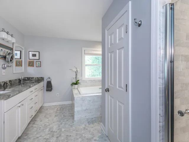 a bathroom with a granite countertop sink a large mirror a bathtub and shower