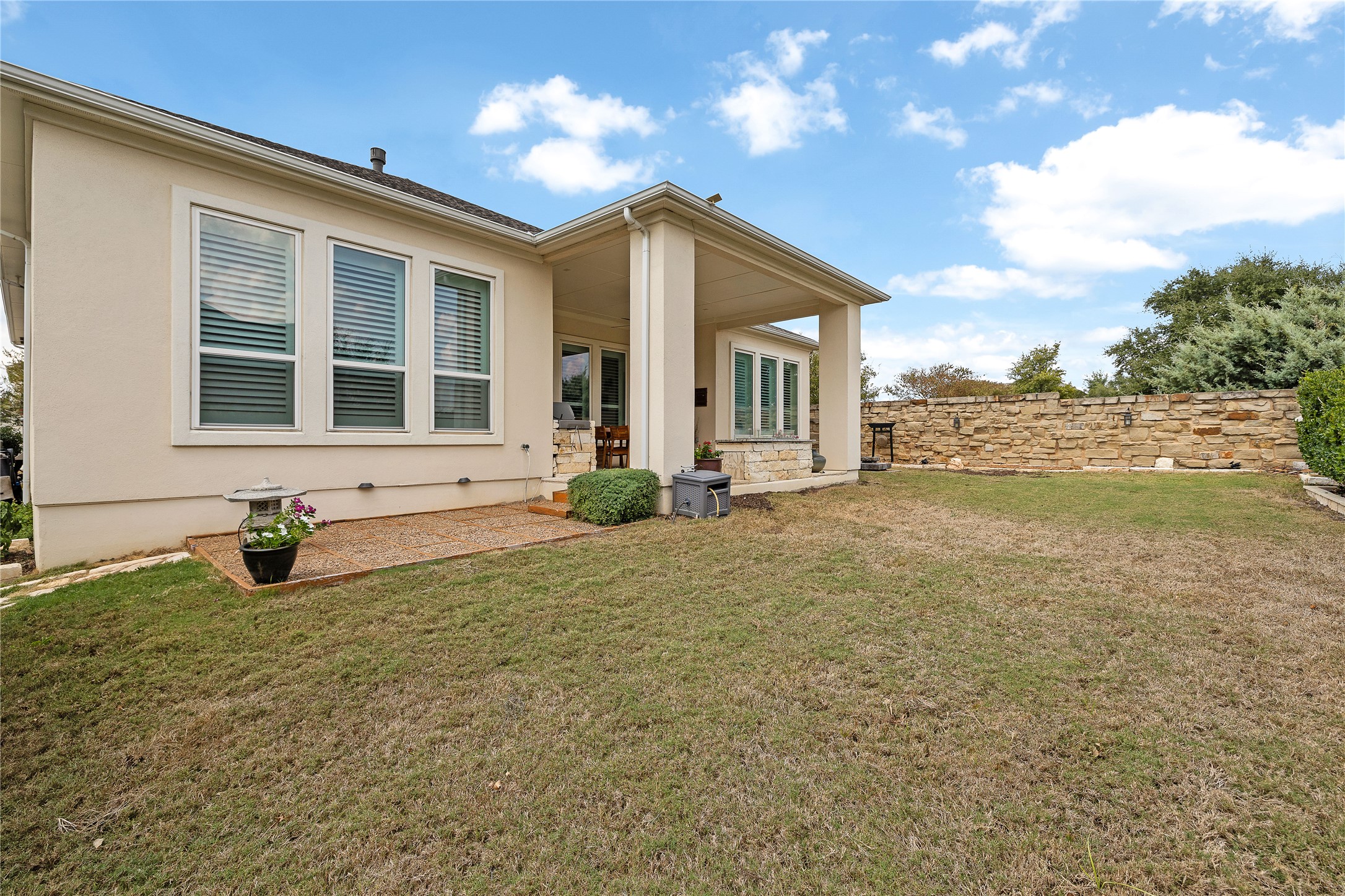 1716 Siena Sunset Road Leander, TX 78641 - Photo 25 of 28 The rear view shows the covered patio and the stone wall along one side of the yard, where there’s no home immediately next door.