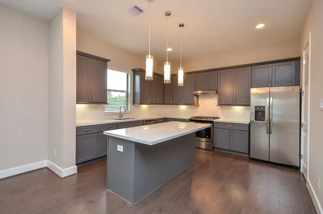 a kitchen with stainless steel appliances granite countertop a sink a stove and a refrigerator