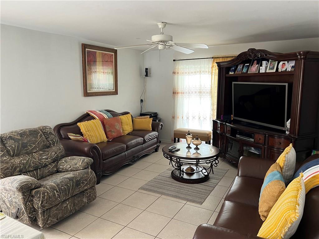 4618 19th Court Southwest Naples, FL 34116 - Photo 7 of 16 a living room with furniture a flat screen tv and a fireplace
