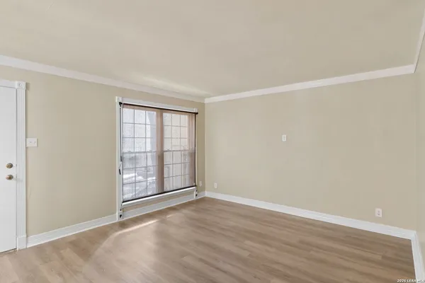 a view of an empty room with wooden floor and a window