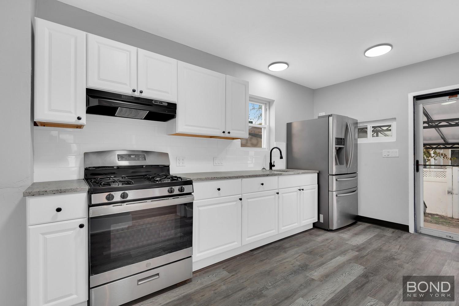 119-73 Merrill Street Queens, NY 11434 - Photo 4 of 12 a kitchen with cabinets stainless steel appliances and wooden floor