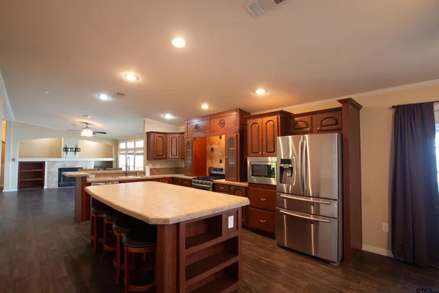 a kitchen with stainless steel appliances kitchen island granite countertop a table chairs and a refrigerator