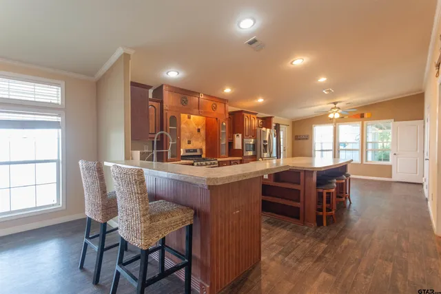 a dining hall with stainless steel appliances granite countertop a stove and a dining table with wooden floor