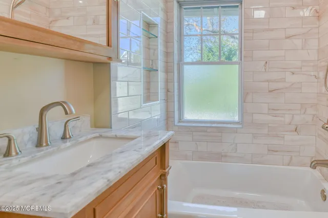 a bathroom with a granite countertop tub a sink and a window