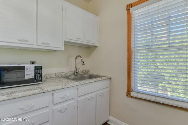 a kitchen with granite countertop white cabinets and a wooden floor