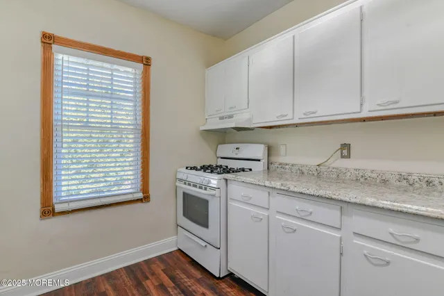 a kitchen with granite countertop white cabinets and a stove