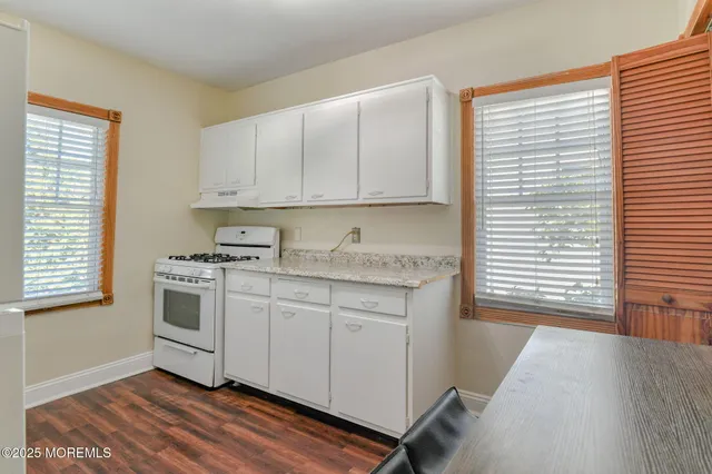 a kitchen with granite countertop white cabinets and white appliances