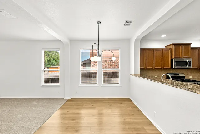 a view of a kitchen with a stove cabinets a ceiling fan and wooden floor
