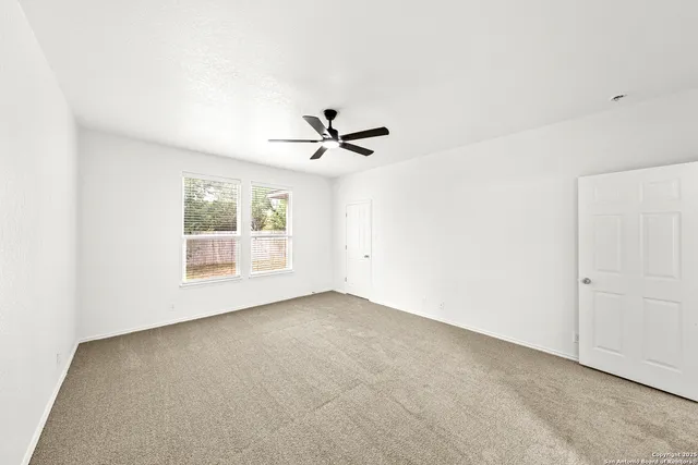 an empty room with a ceiling fan and window