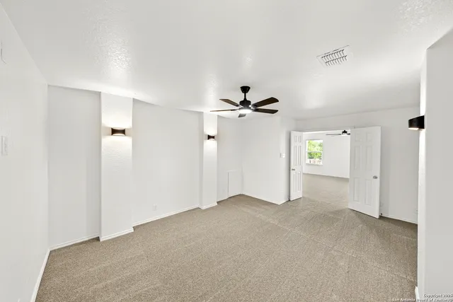 an empty room with windows and fan