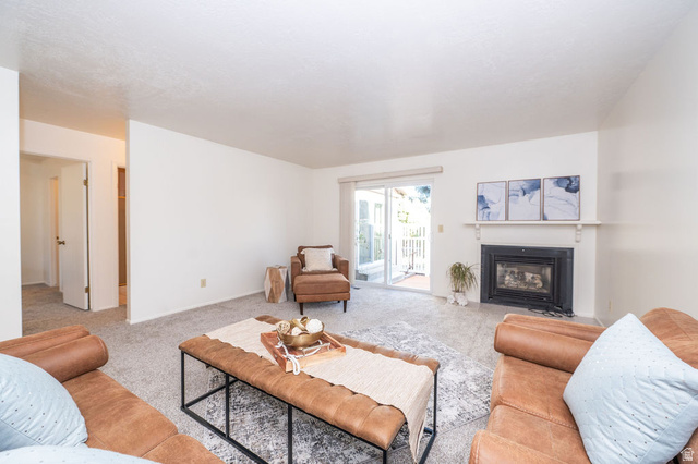 621 Coachman Way Riverdale, UT 84405 - Photo 17 of 38 Living room with light colored carpet and a fireplace with flush hearth. Walk out to rear patio.