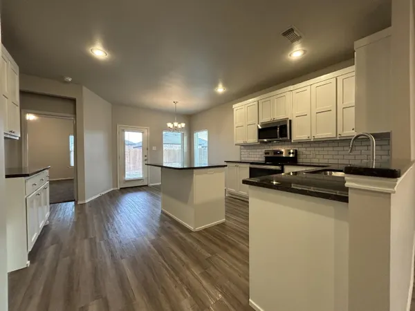a kitchen with stainless steel appliances granite countertop a sink a stove top oven a counter space and cabinets