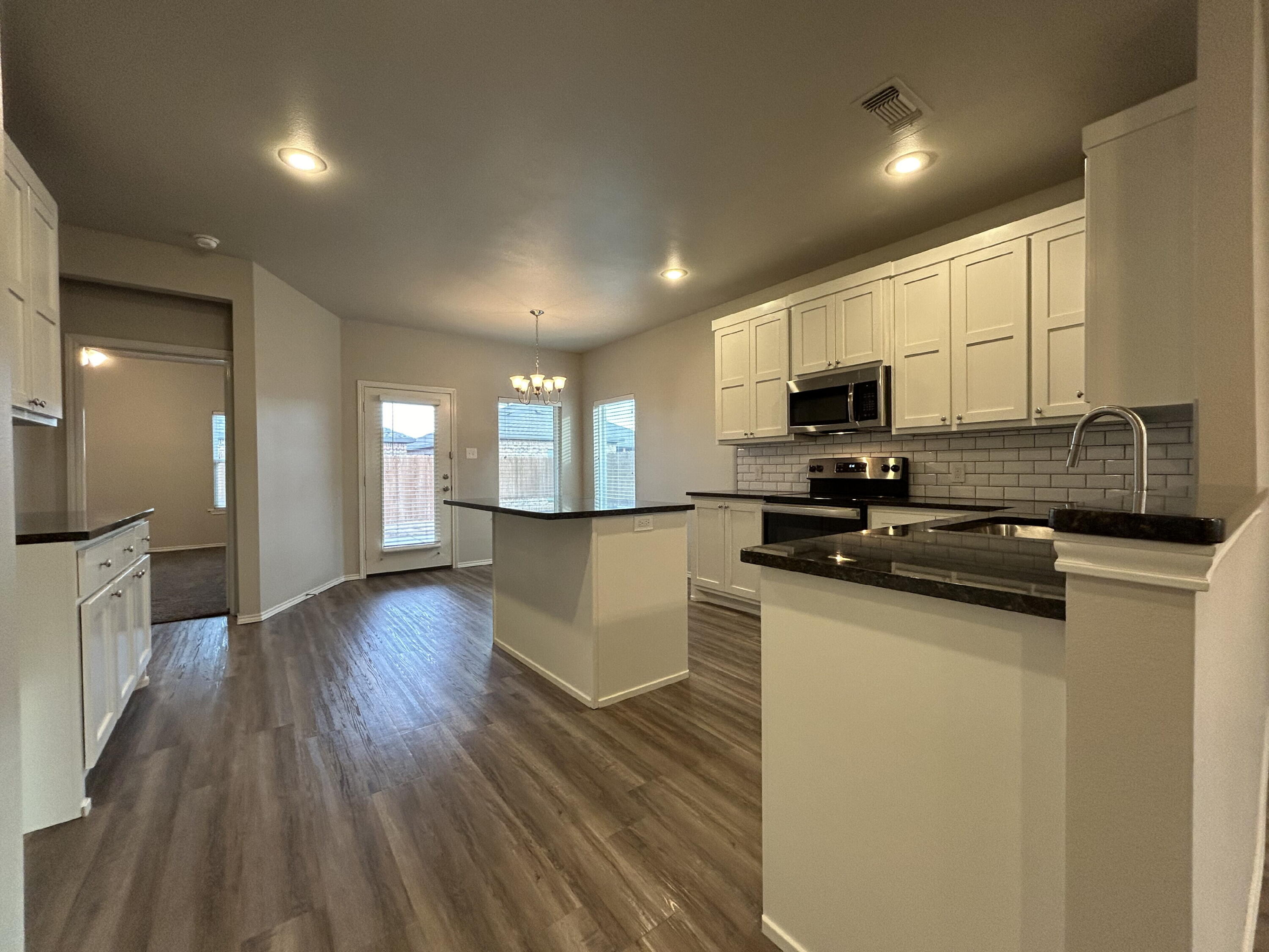 5843 Itasca Street Lubbock, TX 79416 - Photo 3 of 10 a kitchen with stainless steel appliances granite countertop a sink a stove top oven a counter space and cabinets