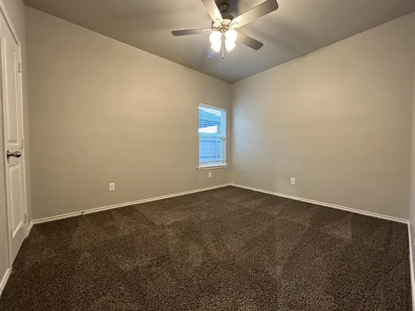 an empty room with a chandelier fan and windows