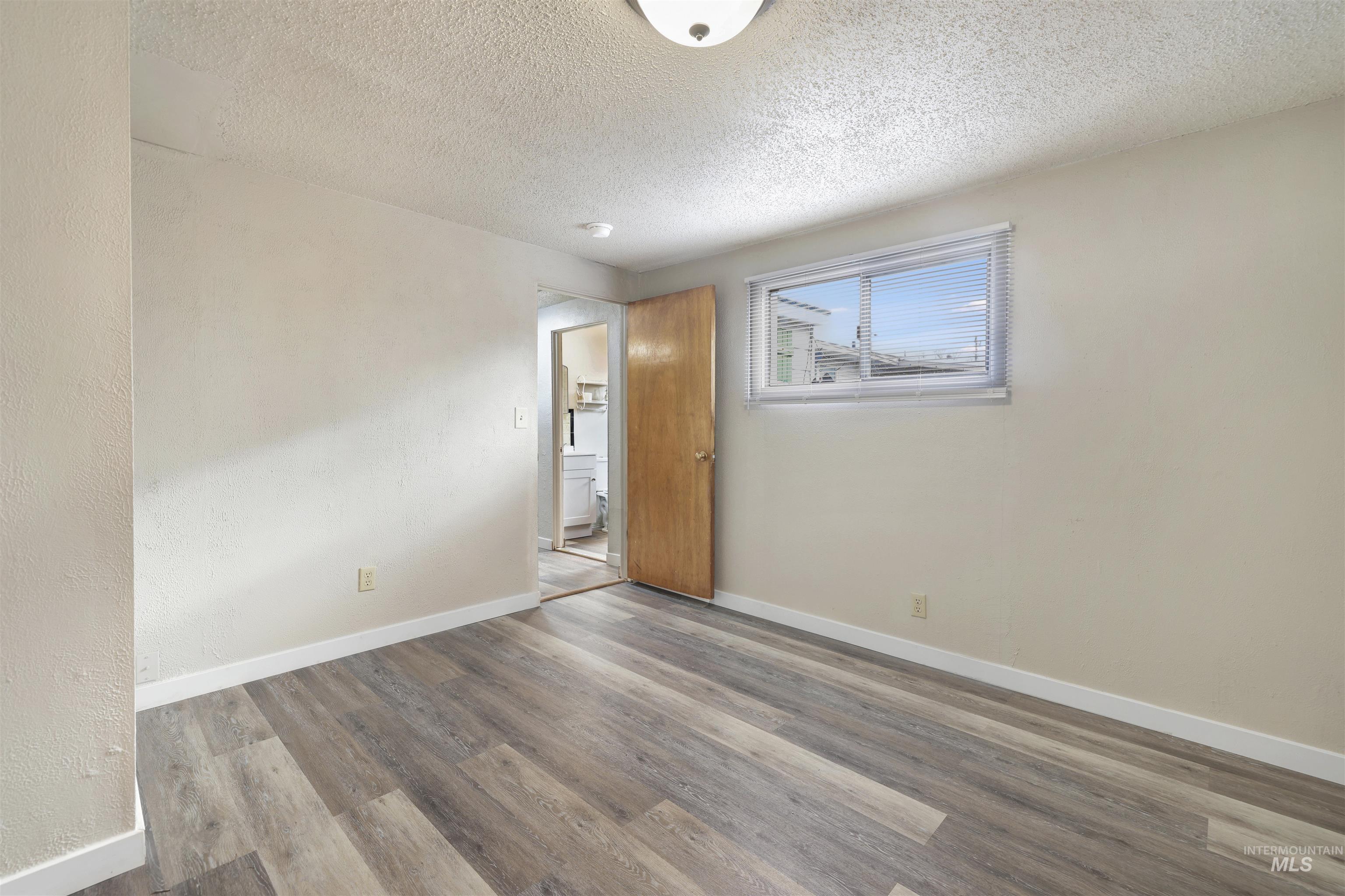 545 Madison Street Twin Falls, ID 83301 - Photo 16 of 23 Spare room featuring wood finished floors, a textured ceiling, and a textured wall