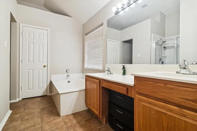 a spacious bathroom with a double vanity sink a mirror and a bathtub